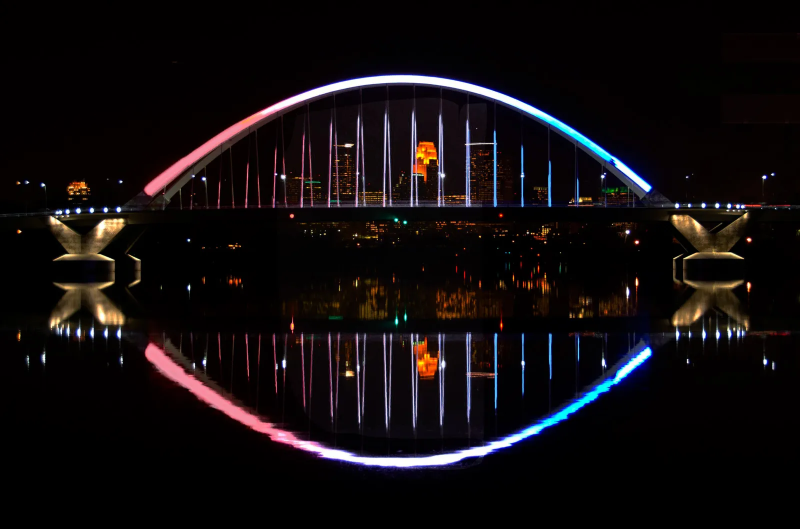 a nighttime photo of the Lowry Avenue Bridge lit up in pink, blue, and white to honor Transgender Day of Visibility