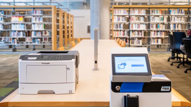 a printer with bookshelves behind it