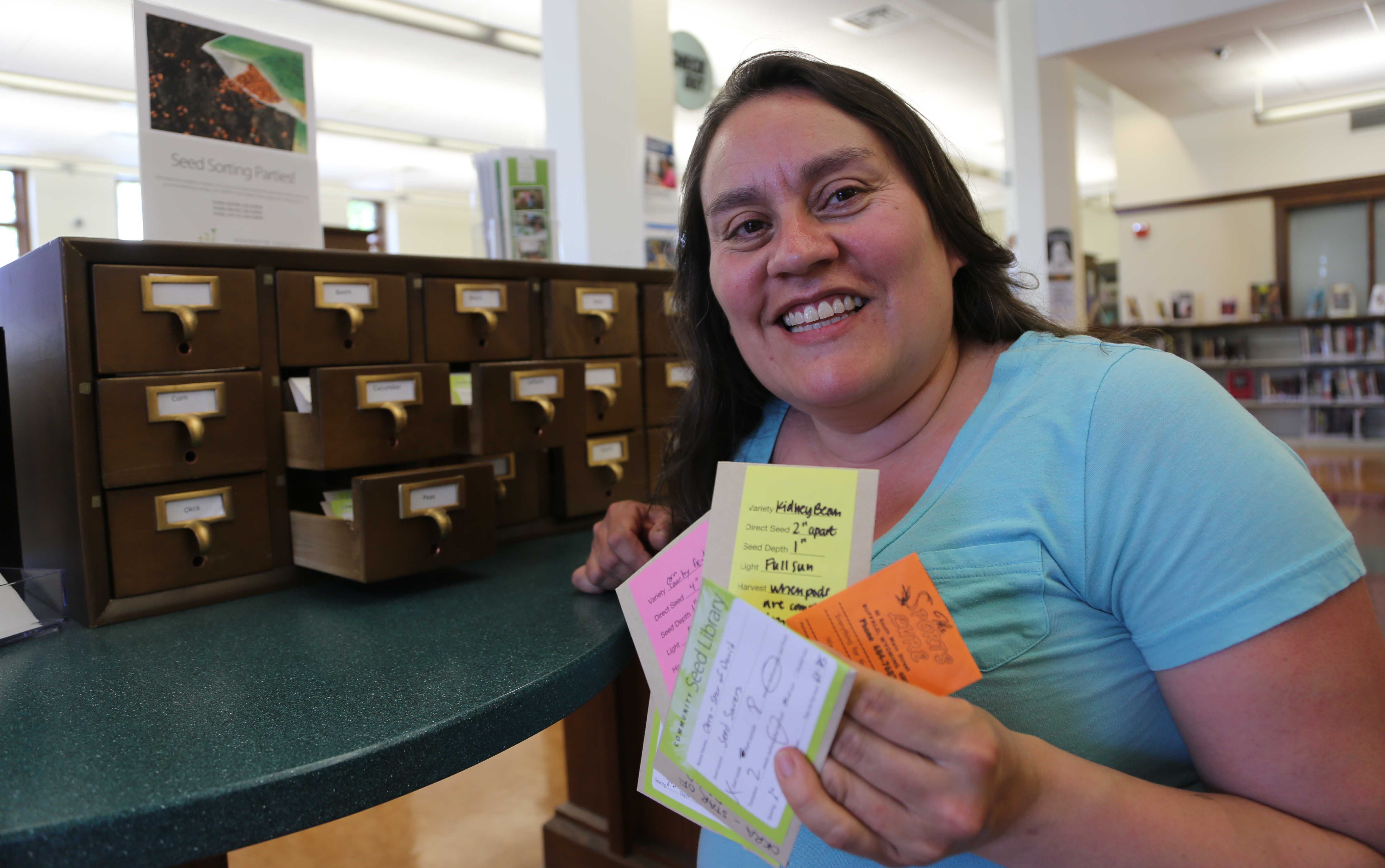 A woman holds seed packets.